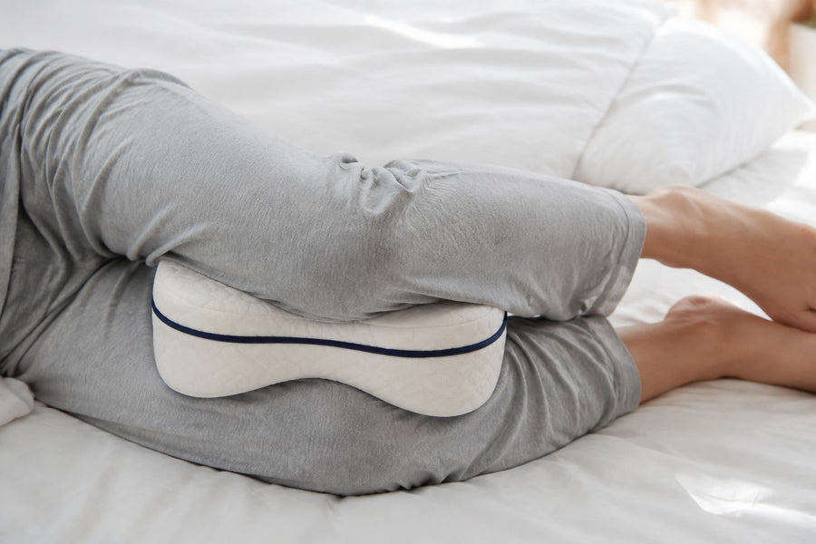 Le coussin calé entre les genoux, allongé sur le côté